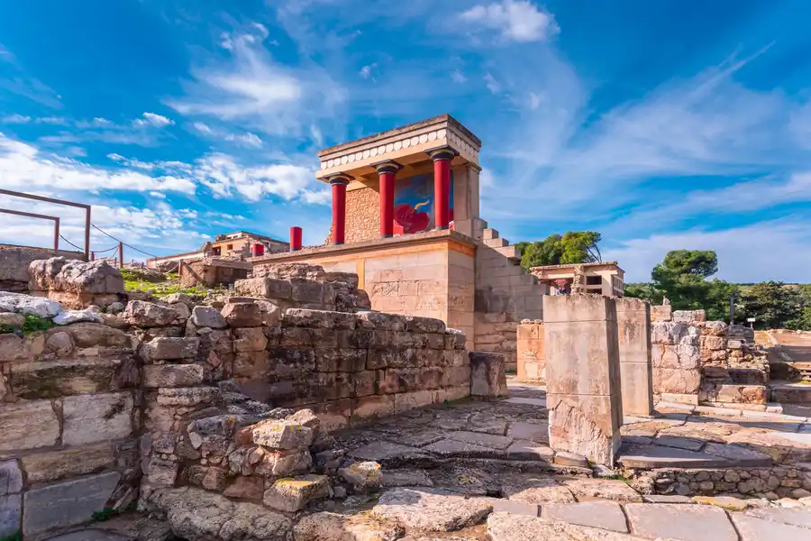 The reconstructed north entrance of Knossos Palace in Crete, with the red columns and charging bull fresco visible in the portico